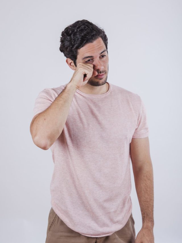 a young man with dry eyes placing his right hand below the right eye